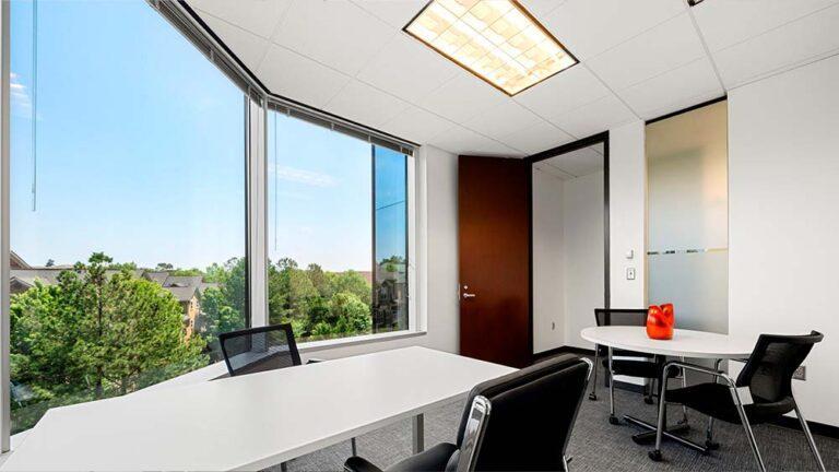 large room with large windows, desk and conference table
