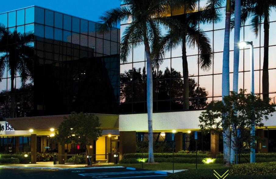 Modern four-story glass office building with tropical landscaping in Boca Raton