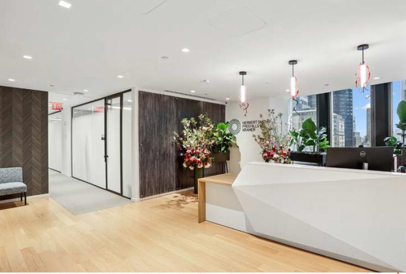 Office reception area with branded wall, modern desk and flower arrangements
