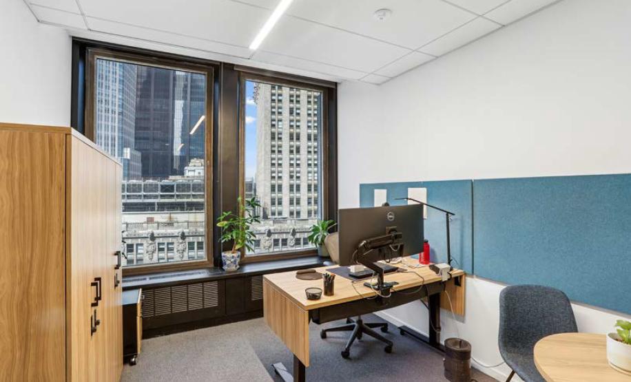 Private office with standing desk, chair and 2 large windows overlooking Midtown Manhattan